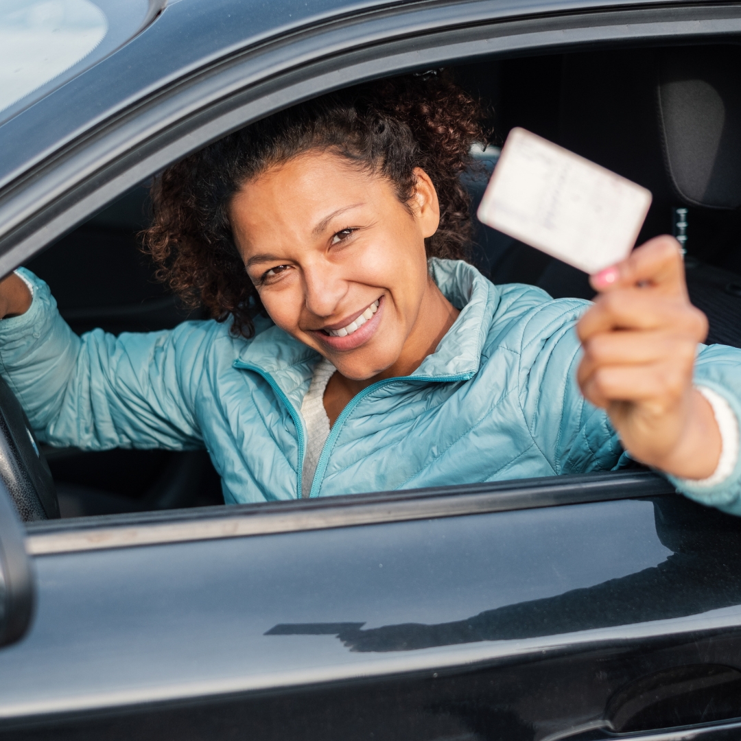 woman holding drivers license in car
