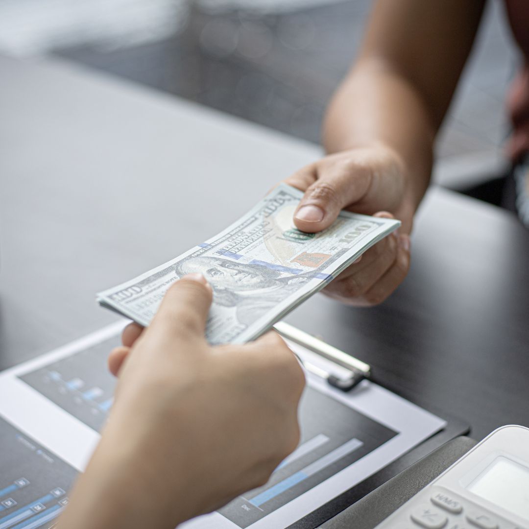 Person handing another person cash. 