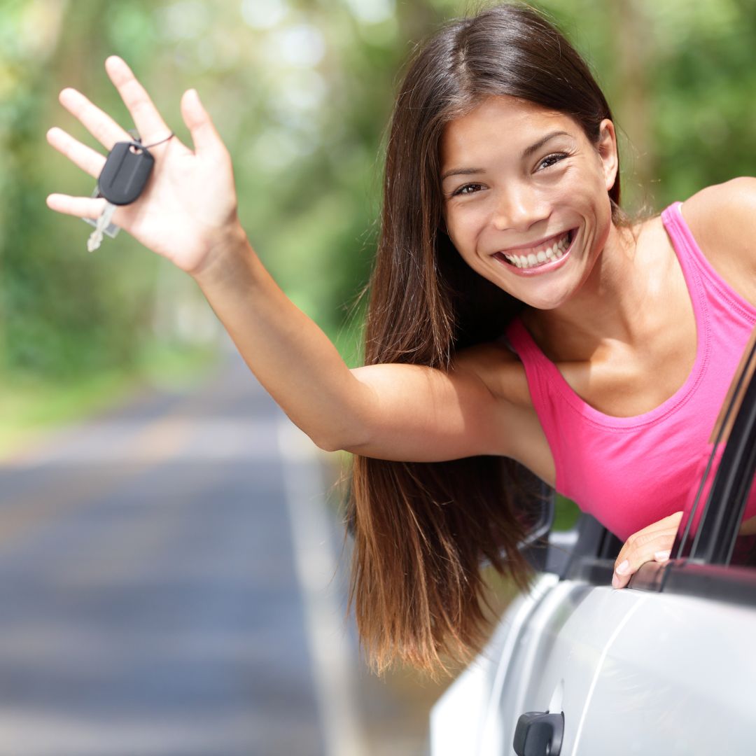 Woman in car waving her keys outside the car's window